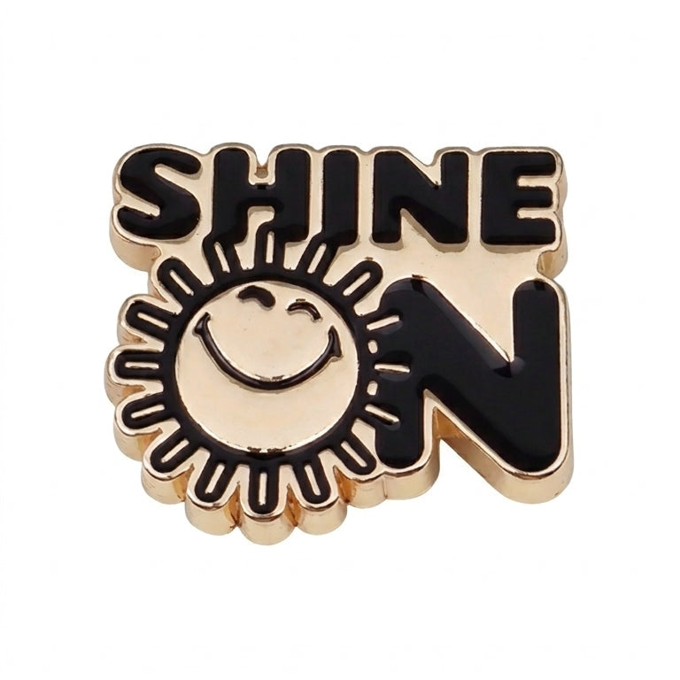 Pin with 'SHINE ON' text and sun design on a white background